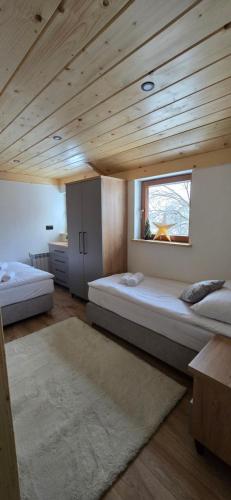 twee bedden in een kamer met een houten plafond bij Apartament u Krupy in Murzasichle