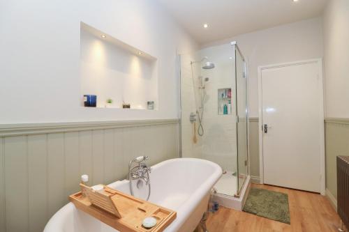 a bathroom with a bath tub and a shower at Waterloo Mill Cottage in Wotton under Edge