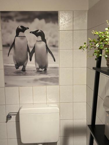 Twee pinguïns staan op het toilet in een badkamer. bij Helpens Hof in Salzhausen