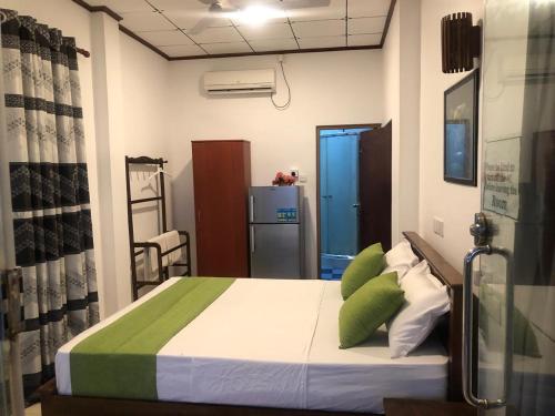 a bedroom with a bed with green and white pillows at Coastal Heaven in Bentota