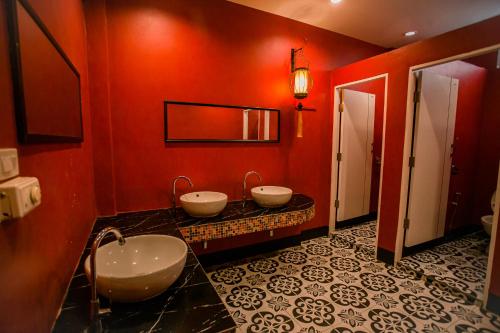 ein Badezimmer mit zwei Waschbecken in einer roten Wand in der Unterkunft De Thaphae Chiangmai in Chiang Mai
