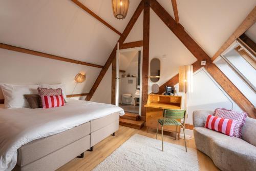 een slaapkamer op zolder met een bed en een stoel bij Hotel het Oude Raadhuis in Castricum