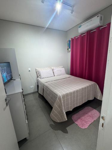 una piccola camera da letto con letto con tende rosa di Casa espaçosa e acolhedora a Ponta Porã