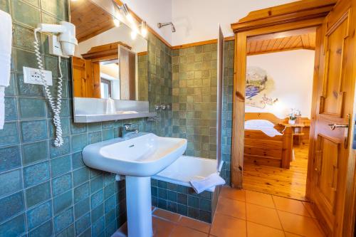 een blauw betegelde badkamer met een wastafel en een bad bij Villaggio Hotel Aquila in Calliano