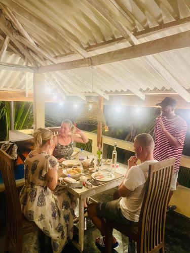 Un grupo de personas sentadas alrededor de una mesa comiendo en Amour Surf, en Tangalle