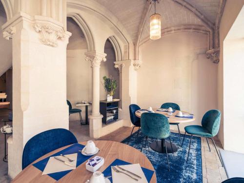 ein Esszimmer mit Tischen und Stühlen und einer Decke in der Unterkunft Mercure Poitiers Centre in Poitiers