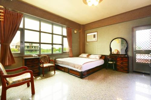 a bedroom with a bed and a chair and windows at Jheng Tong House in Dayin