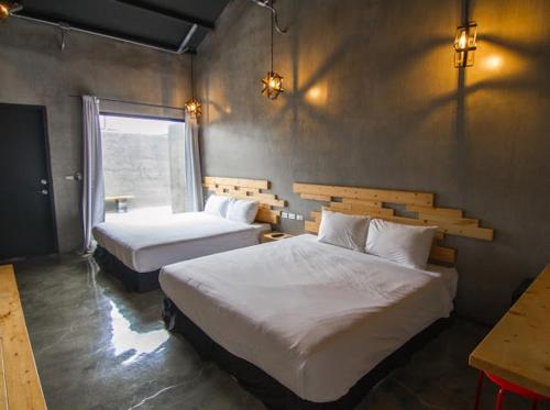 een slaapkamer met twee bedden en een raam bij Kenting Xia Ye B&B in Hengchun