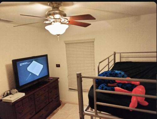 a bedroom with a bed with a television and a ceiling fan at La casa in Winter Haven