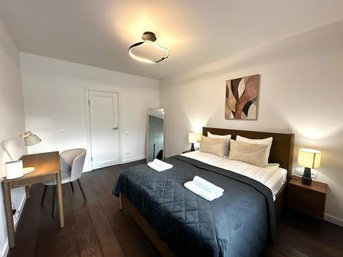 a bedroom with a large bed and a desk and a lamp at Panoramic River View I Spacious Modern 2BR Apartment in Riga