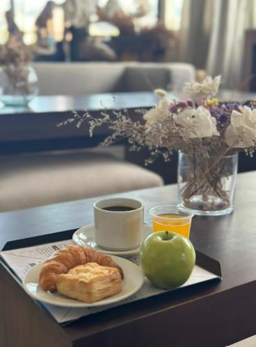 ein Tablett mit einem Teller Essen, einer Tasse Kaffee und einem Apfel in der Unterkunft Hotel Internacional in Mendoza