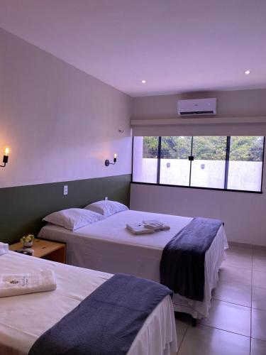 a hotel room with two beds and a window at Pousada Primavera in Parnaíba