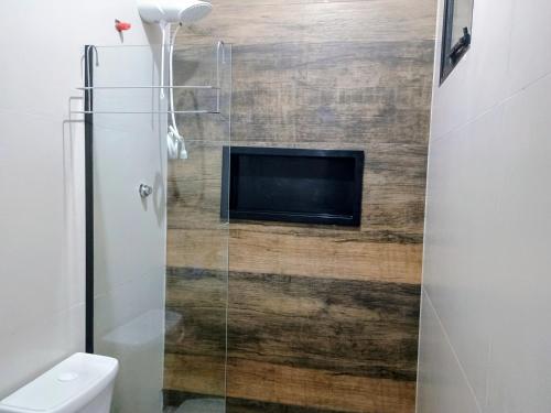 a bathroom with a toilet and a tv on a wall at Flat confortavel e aconchegante in Cabo Frio
