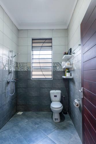 a bathroom with a toilet and a shower and a window at Mivida Residences in Bulindo