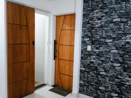 a hallway with two wooden doors and a brick wall at Flat confortavel e aconchegante in Cabo Frio