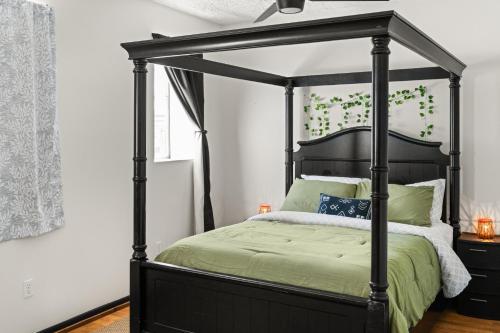 a bedroom with a black canopy bed with green sheets at Circle Overlook-Downtown Apartment Stay in Sebring