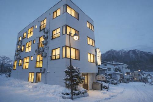 a building with lights on in the snow at AURA YUZAWA Apartment Hotel - Spacious 1Bedroom Apartment with Large Living Room Sleeps 4 to 6, Bedroom with 2-Double Beds, Living Room with 1-Double Bed & 1-Sofa Bed in Yuzawa
