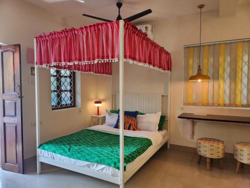 a bedroom with a four poster bed with a red canopy at Florin Studio in Vagator