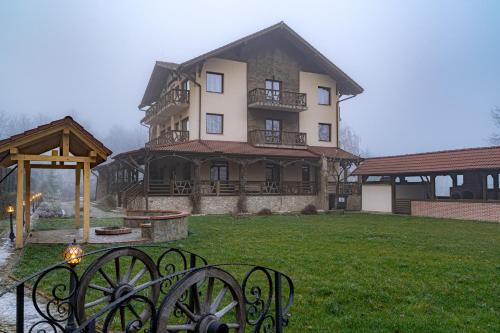 een groot huis met een poort aan de voorkant, grenzend aan een tuin bij Vâlceaua Zânelor in Stațiunea Climaterică Sâmbăta
