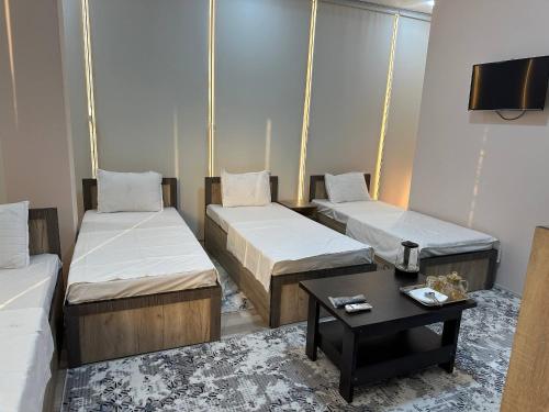 Cette chambre comprend 2 lits et une table basse. dans l'établissement Rubin Hotel, à Navoï