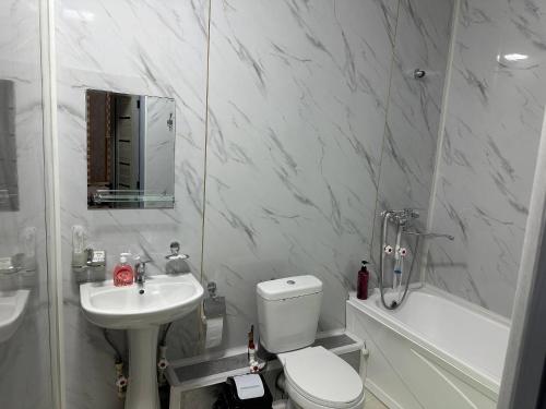 une salle de bains blanche avec toilettes et lavabo dans l'établissement Rubin Hotel, à Navoï