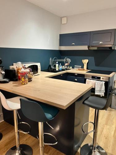 een keuken met een houten aanrecht en 2 barkrukken bij Confort appart in Oyonnax