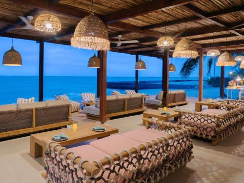 七岩SO/ Sofitel Hua Hin的度假村大堂里摆放着沙发和桌子，还能看到大海。