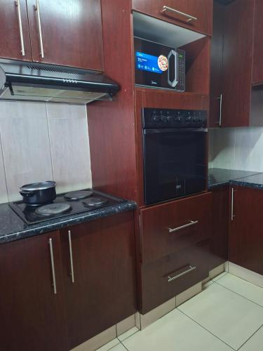 une cuisine avec des armoires en bois et un four à plaques de cuisson dans l'établissement Number 8, à Maseru