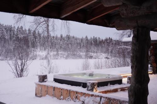 a hot tub in a snow covered yard at Villa Tolonen a beautiful log villa by the Ivalo River in Ivalo