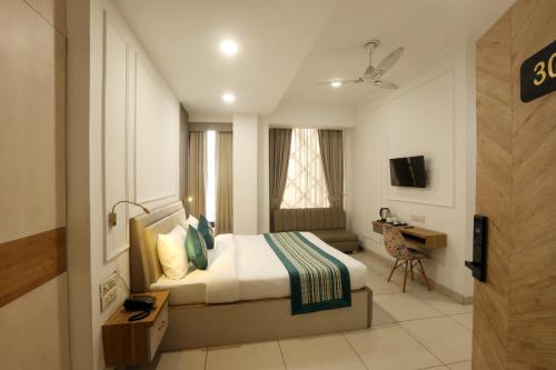 a bedroom with a bed and a desk and a television at Hotel Emerald Suites By Aura in Noida