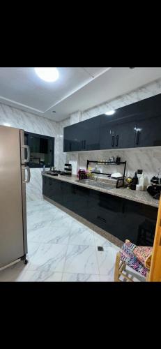 een keuken met zwarte kasten en een aanrecht bij Shahd in Meknès