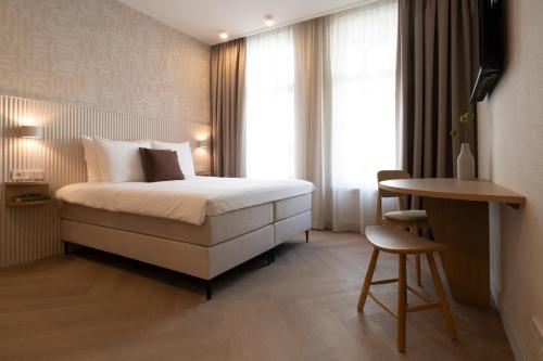 a bedroom with a bed and a table and a desk at Hotel Zest Den Haag - Scheveningen in Scheveningen
