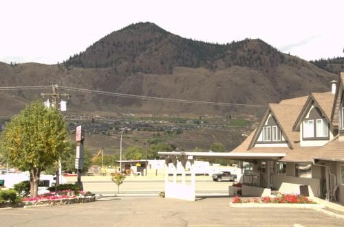 a building in a parking lot with a mountain in the background at Best Budget Inn & Suites Kamloops in Kamloops
