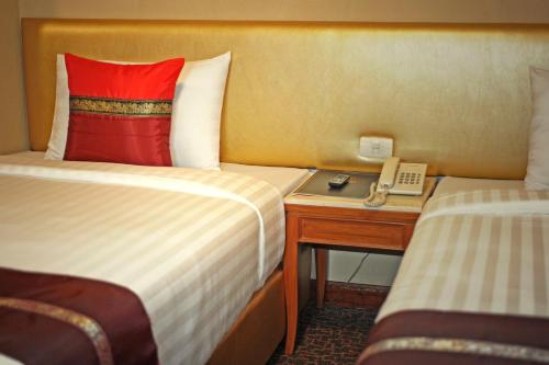 a hotel room with two beds and a phone on a desk at Nasa Bangkok in Bangkok