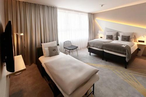 een hotelkamer met twee bedden en een stoel bij Holiday Inn - the niu, Coin Frankfurt Ostend by IHG in Frankfurt am Main