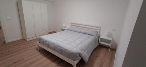 a white bedroom with a bed and a wooden floor at Casa vacanza del Cavallo in Senigallia