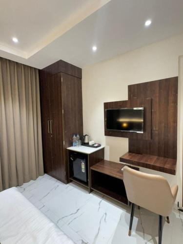a room with a bed and a desk and a television at Aero Lounge Hotel in Jāmb
