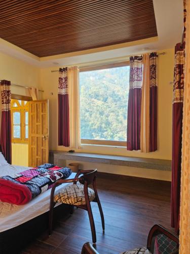 a bedroom with a bed and a large window at Jaibari Basa in Ukhimath