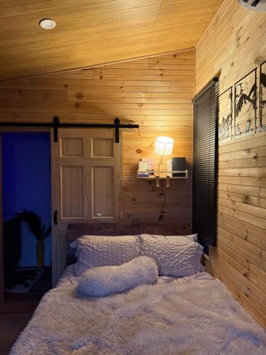 una camera da letto con un letto in una parete di legno di Forava Cabins a Ringwood