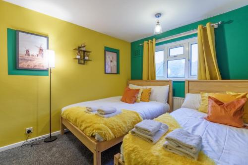 two beds in a room with green and yellow walls at Open Mind Property- Hot Tub, Sleeps 9 & Free Parking in Portsmouth
