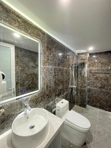 een badkamer met een wastafel, een toilet en een spiegel bij Diamond Hotel in Long Biên