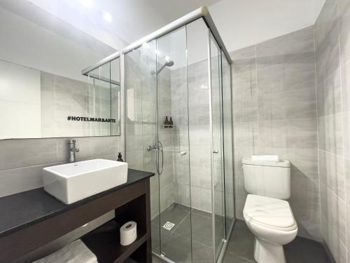 a bathroom with a shower and a toilet and a sink at Hotel Mar y Arte in Piriápolis