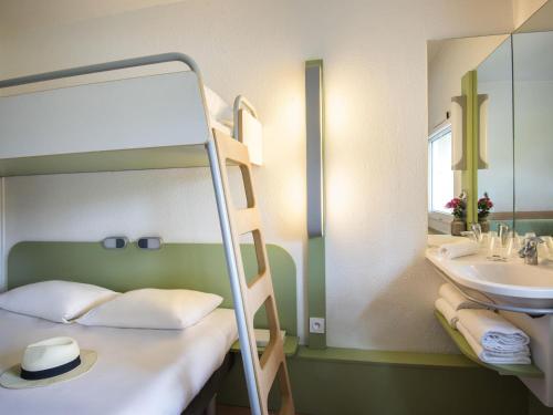 une chambre avec un lit superposé avec un lavabo et un miroir dans l'établissement IBIS Budget Aix en Provence Est Le Canet, à Meyreuil