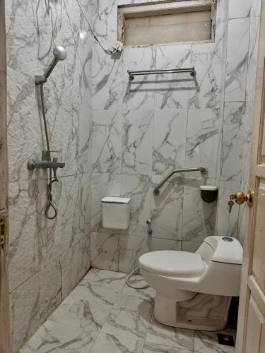 a white bathroom with a toilet and a shower at Omah Putih Jogja in Yogyakarta