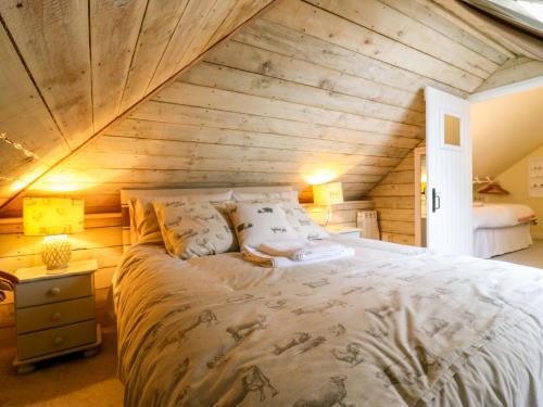 a large bed in a room with a wooden ceiling at The Hayloft - Beautiful Barn Stay in Ashford