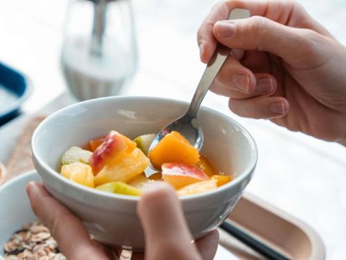 a person eating a bowl of fruit with a spoon at ibis budget Carcassonne La Cité in Carcassonne