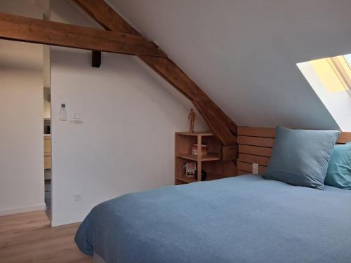 ein Schlafzimmer mit einem blauen Bett in einem Dachgeschoss in der Unterkunft Gîte du Papillon CALUTRE Domaine du Papillon CALUTRE in Carvin