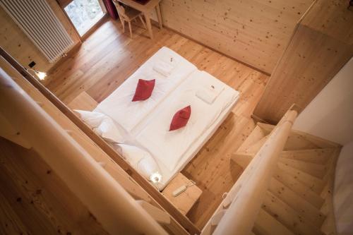 Draufsicht auf ein weißes Bett mit roten Kissen in der Unterkunft Maso Fior di Bosco - Val di Rabbi - Esercizio Rurale in Rabbi