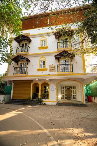 a large white building with windows on a street at Lume Stayz in Siolim