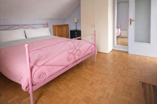 een roze bed in een kamer met een houten vloer bij Mansarda Panoramica nelle Valli di Lanzo Camino & Silenzio in Ceres